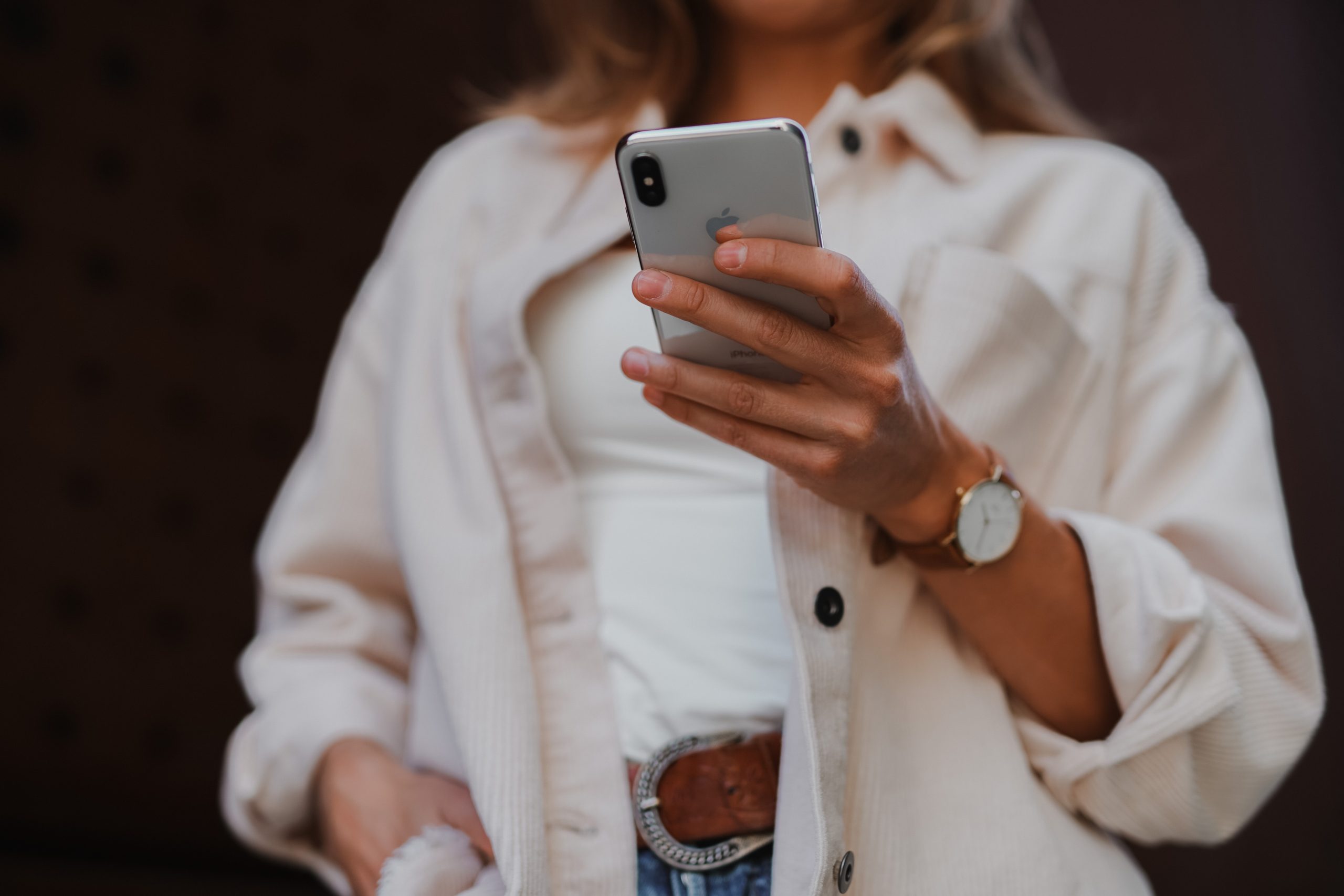 Blurred female marketing and advertising specialist in background holding a cell phone in sharp focus.