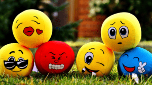 Colorful stress balls with emoticon faces showing various emotions outside on grass