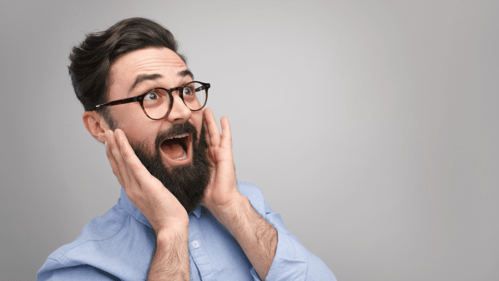 Man with a beard and glasses showing a surprised face as an example of the role of emotional triggers in consumer behavior